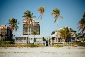 Sunny beachfront view with palm trees and modern houses, perfect for a tropical getaway.